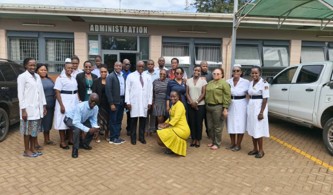 a group of people (delegation participants) standing in front of a hospital building 